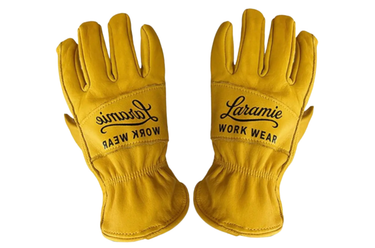 A pair of mustard yellow leather work gloves with black embroidered 'Laramie Work Wear' branding on the backs, displayed against a solid white background.